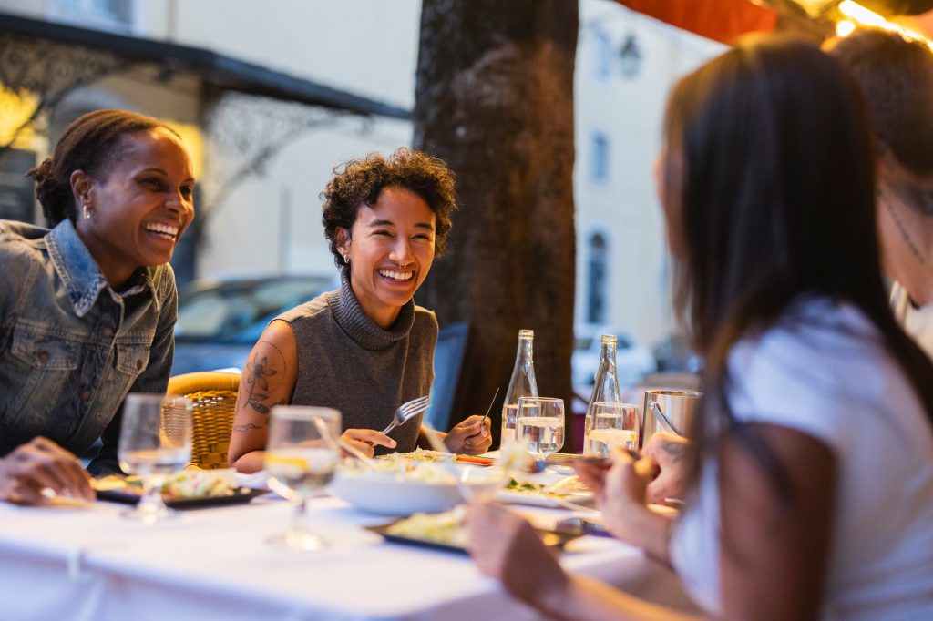 Friends enjoying dinner together, laughing and talking at restaurant in lisbon, portugal